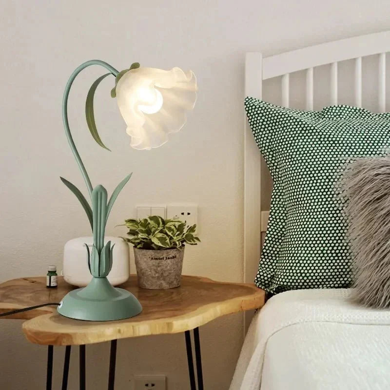 Grønn bordlampe tent på nattbord i soverom
