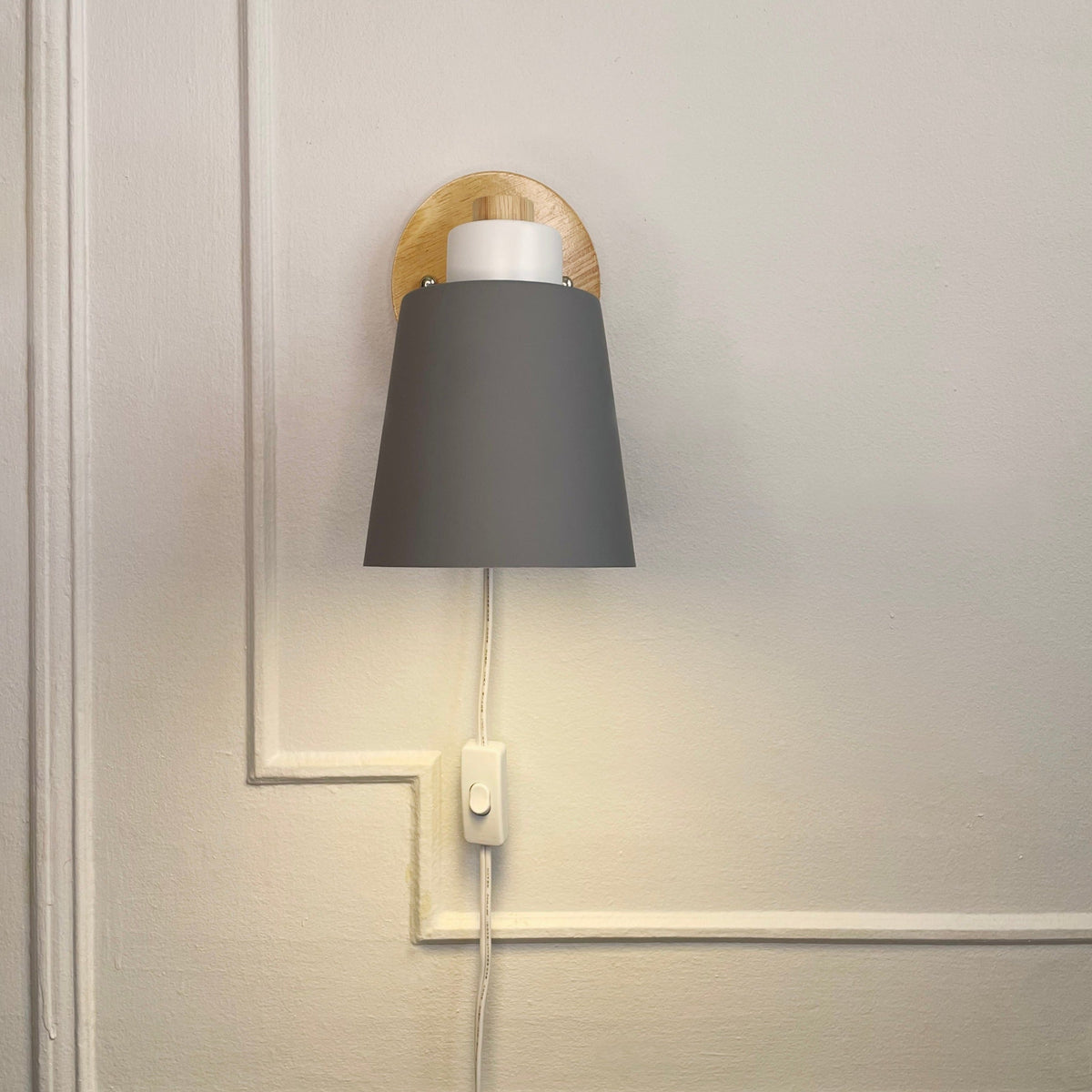Vegglampe med grønn metallskjerm og trebakplate – nærbilde