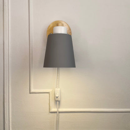 Vegglampe med grønn metallskjerm og trebakplate – nærbilde