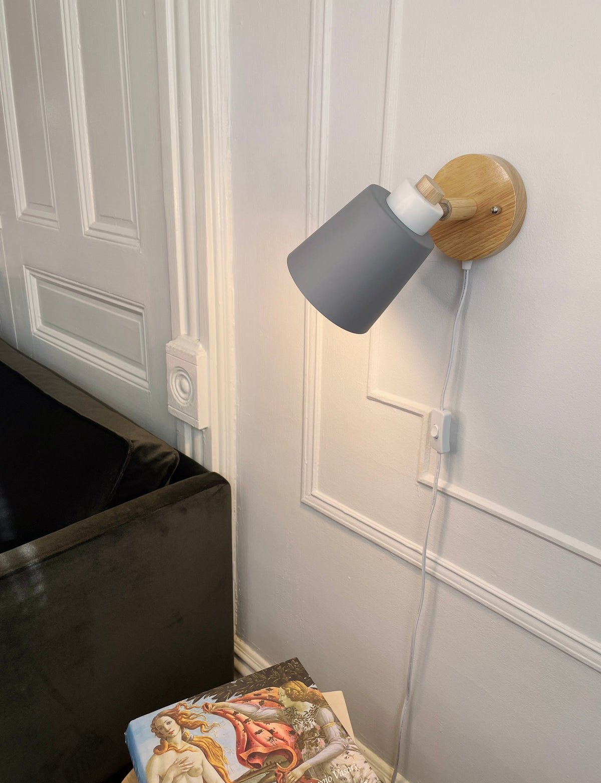 Vegglampe med hvit metallskjerm og treplate montert på vegg