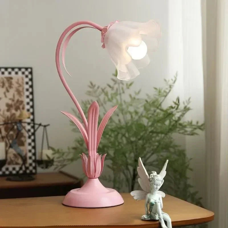 Rosa bordlampe med blomsterdesign på nattbord